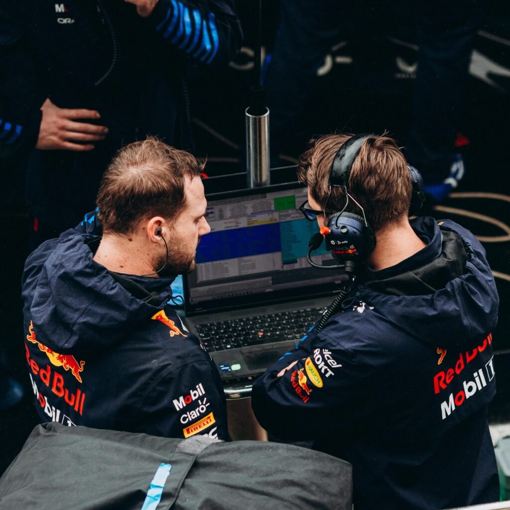 Two Formula 1 team members in discussion over race data at a pit stop.